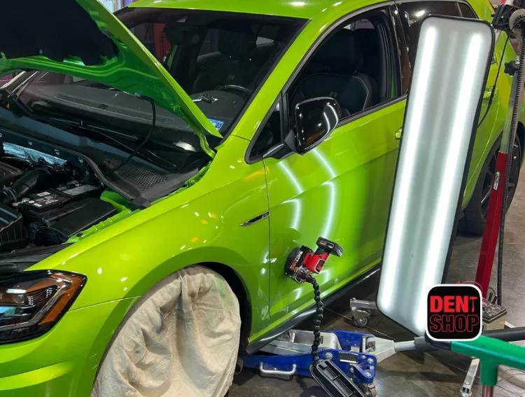 green car receiving paintless dent repair at dent shop